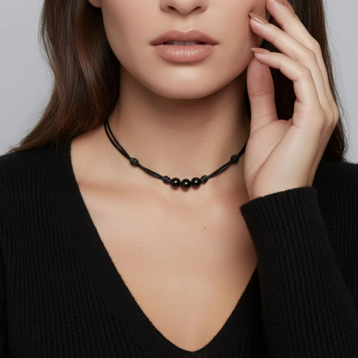 Woman wearing a black beaded necklace against a neutral background