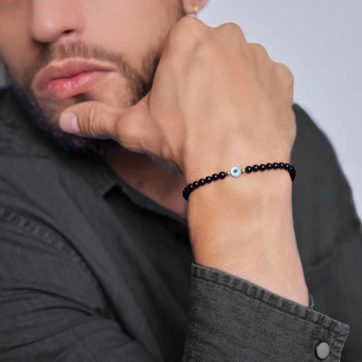 14K Gold and Black Tourmaline bracelet with Mother of Pearl evil eye on a wrist, highlighting the gold accents and snug fit - Luck Strings