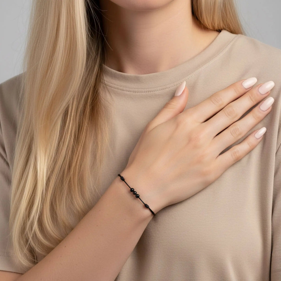 Woman wearing triple black tourmaline round bead bracelet on black nylon cord.