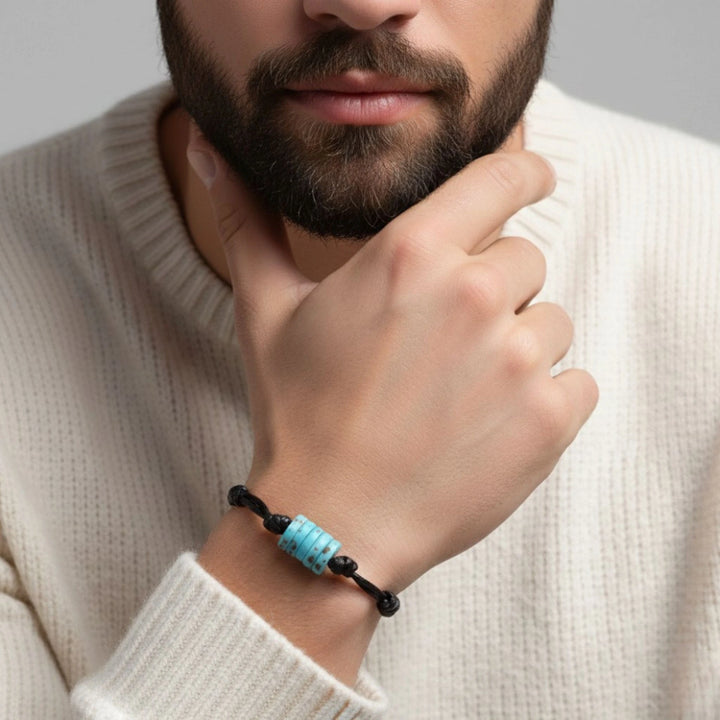Man wearing adjustable turquoise bone bead bracelet on black cord.
