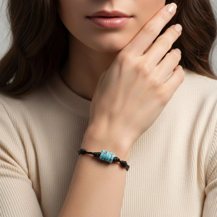 Close-up of a person wearing a turquoise bone beads bracelet  on a neutral background