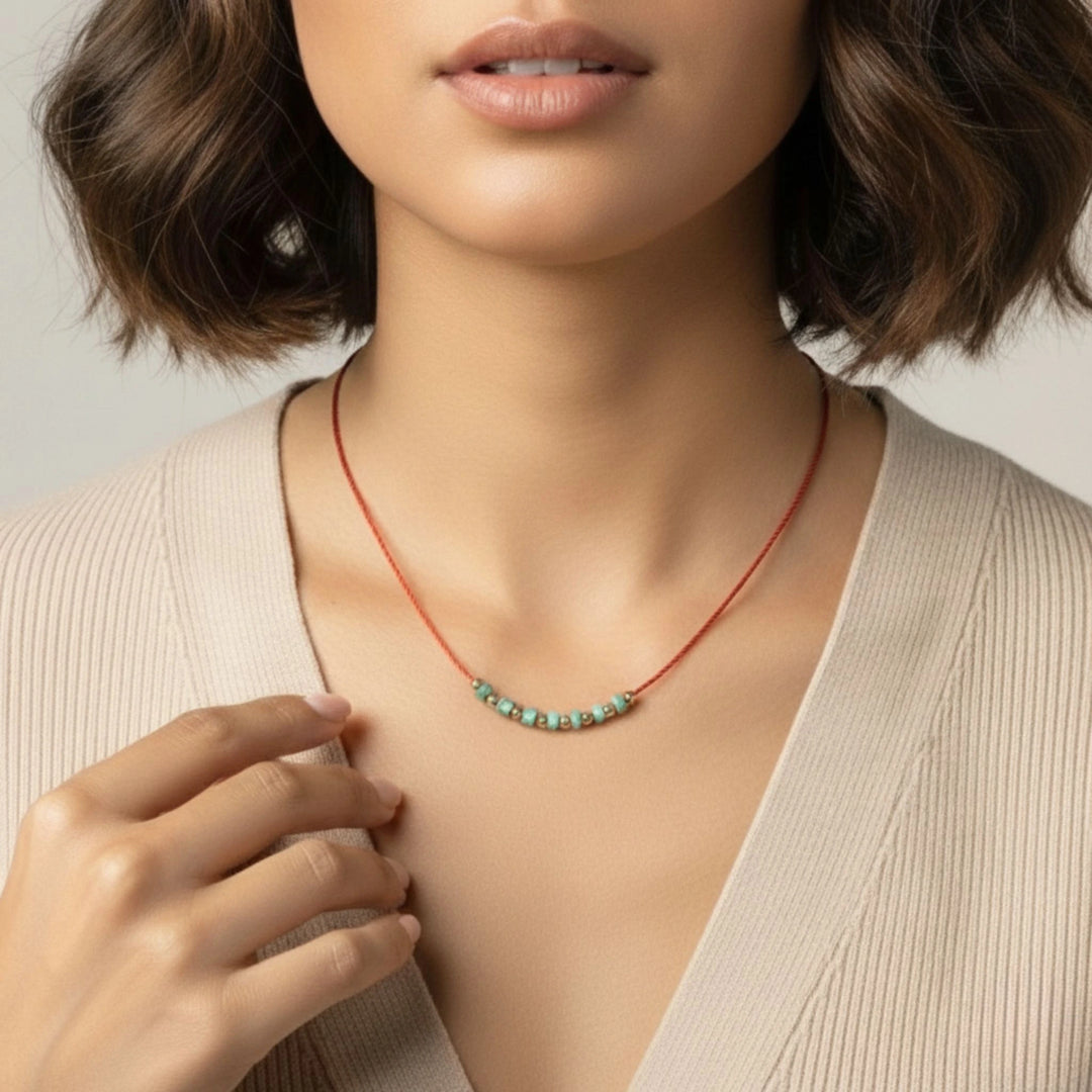 Necklace with turquoise beads worn by a person against a neutral background