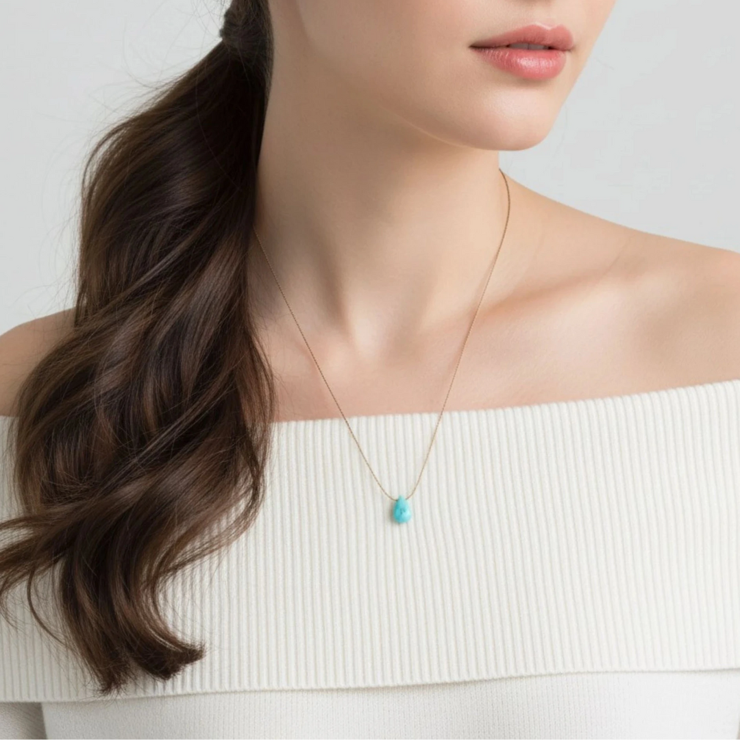 Woman wearing a necklace with a turquoise pendant on a plain background