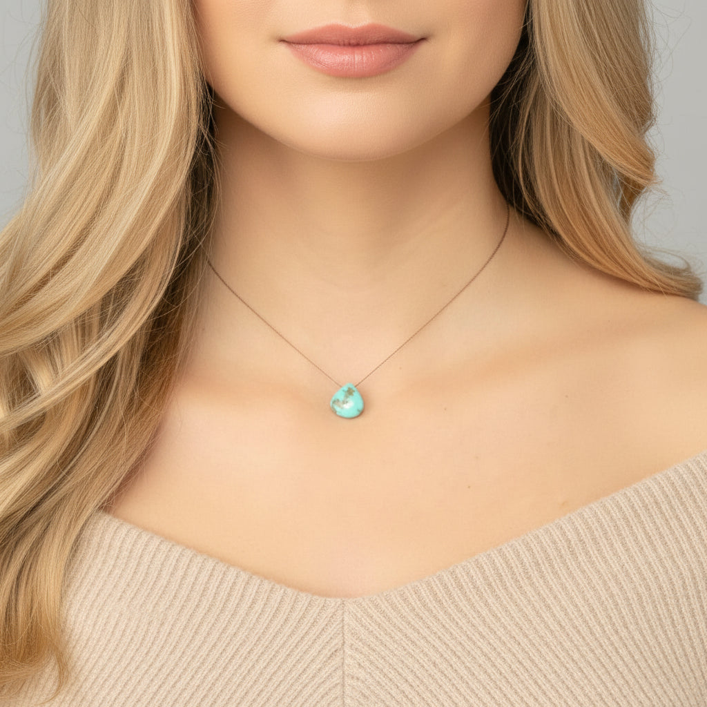 Necklace with a turquoise pendant worn by a person with blonde hair.