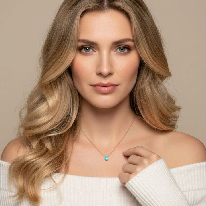 Woman wearing a necklace with a turquoise pendant against a beige background