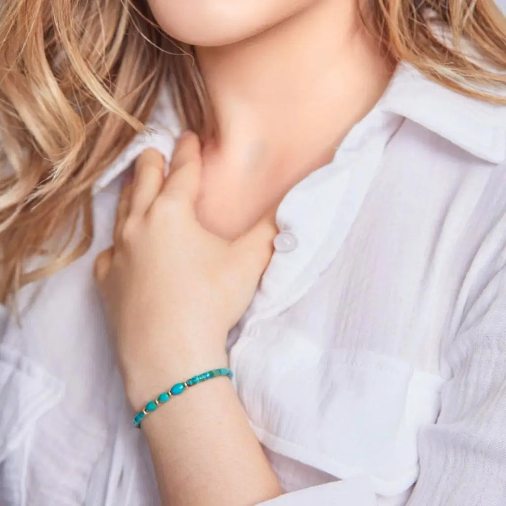 Genuine turquoise heishi and solid gold bracelet on woman's wrist, showcasing minimalist elegance. Luck Strings