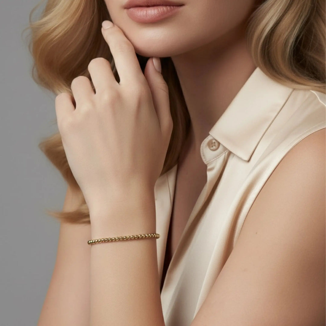 Woman wearing a gold bracelet on a neutral background