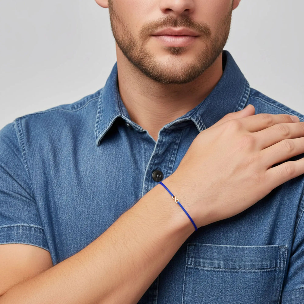 Man wearing a blue denim shirt with a close-up of his wrist showing a blue infinity bracelet.