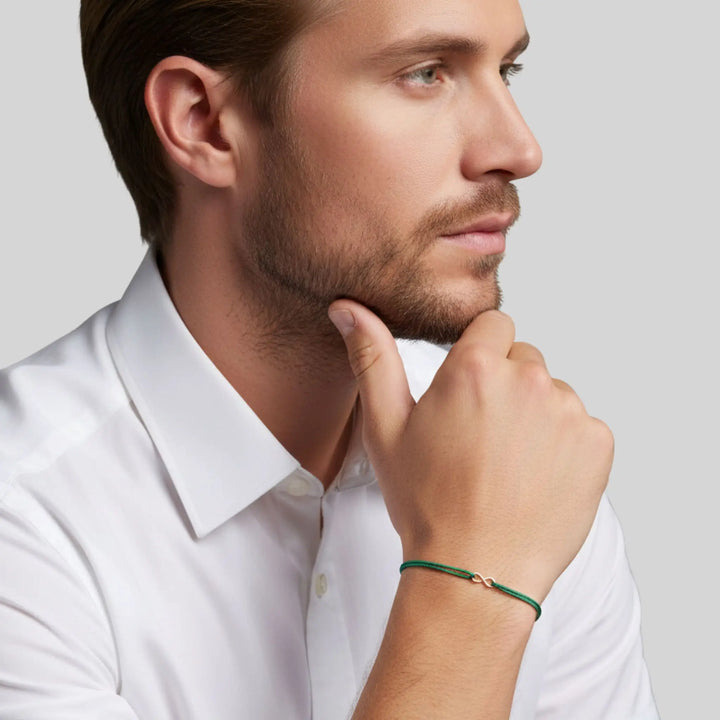 Man wearing a white shirt with a green infinity  bracelet on a light gray background