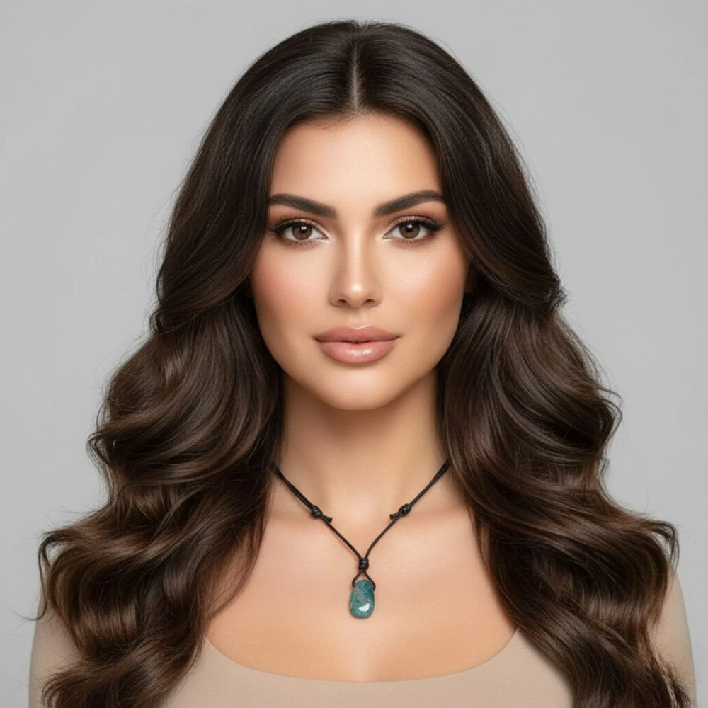 Woman with long, wavy brown hair wearing an Apatite necklace against a gray background