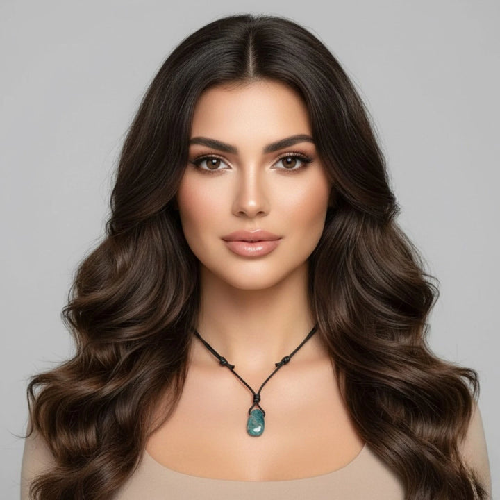 Woman with long, wavy brown hair wearing an Apatite necklace against a gray background