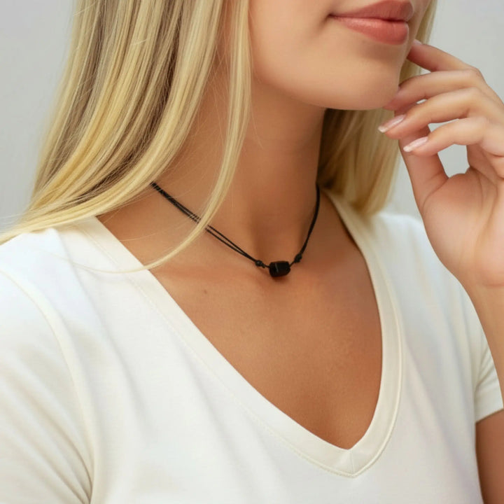 Woman wearing a black tourmaline necklace with a plain background