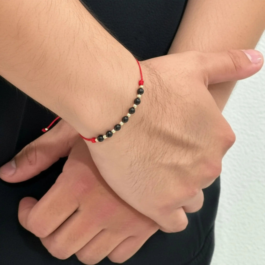 Close-up of a wrist wearing a red, black, and white beaded bracelet.