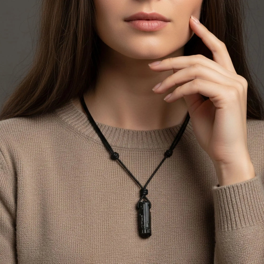 Person wearing a black tourmaline necklace with a pendant against a neutral background