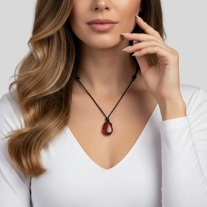 Woman wearing a necklace with a red carnelian pendant against a white background
