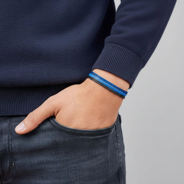 Person wearing a blue bracelet on a plain background