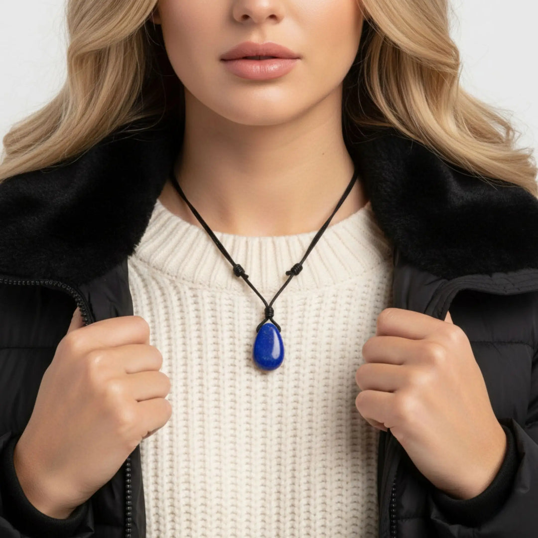Woman wearing a black jacket with a white sweater and a blue lapis lazuli  pendant necklace.