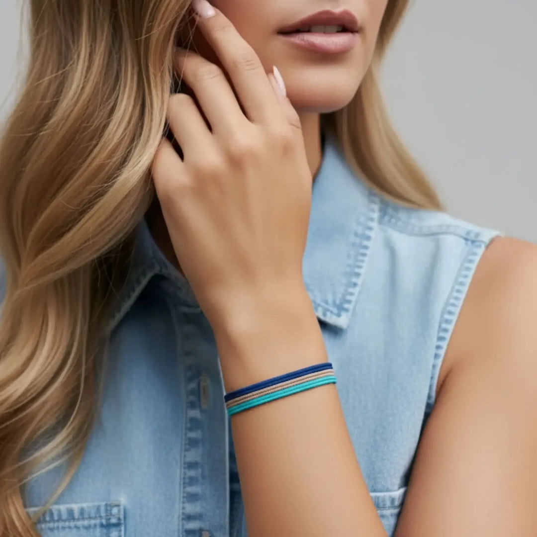 Woman wearing a denim vest with a close-up of her hand and bracelet.