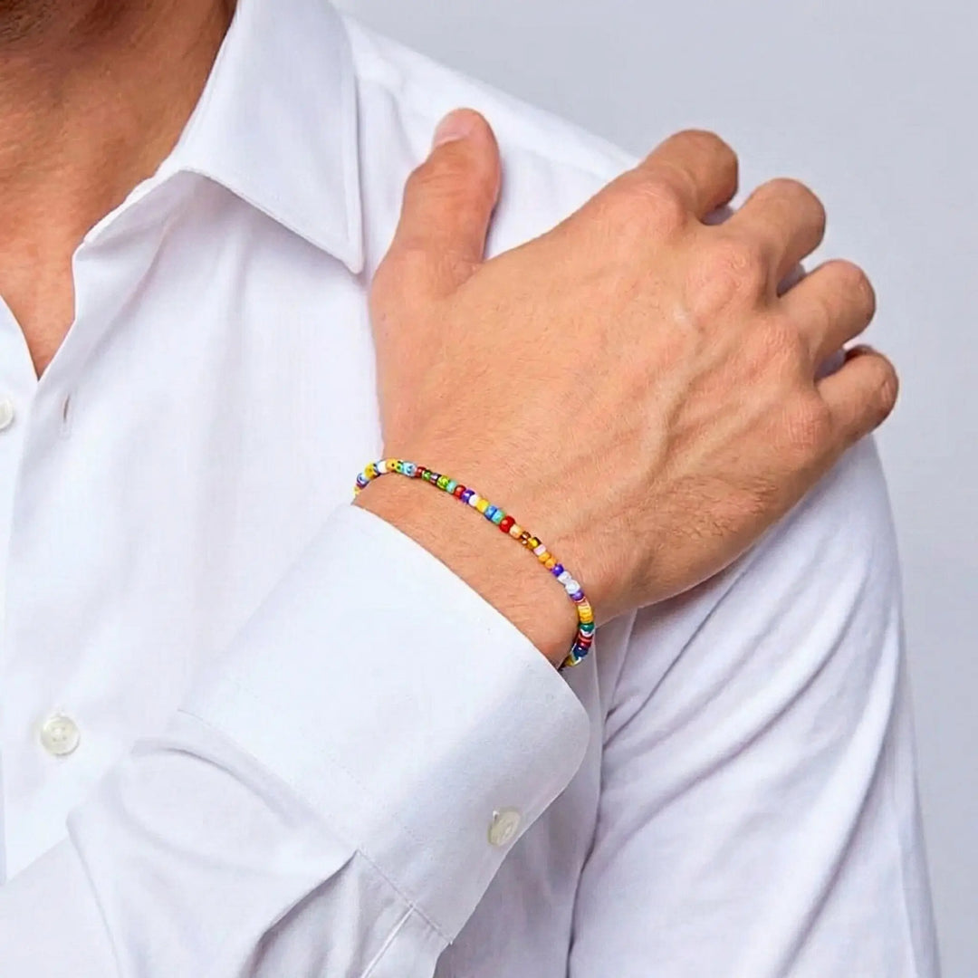 Person wearing a colorful beaded bracelet on a plain background