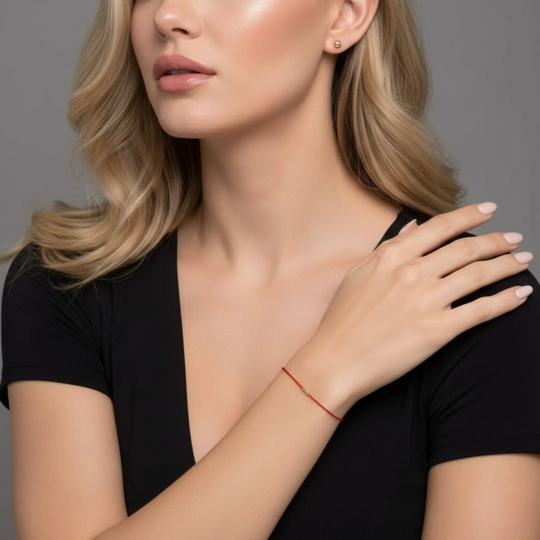 Woman wearing a black top with a red bracelet on a gray background