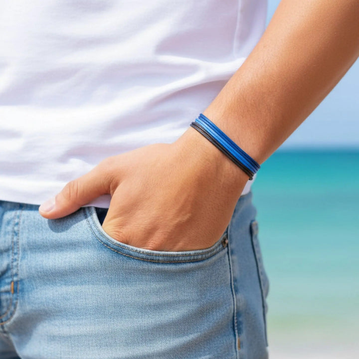 Person wearing a blue bracelet with a blurred beach background