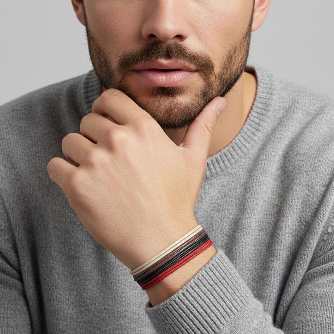 Man wearing a gray sweater with a close-up of his hand and wrist showing multiple bracelets.