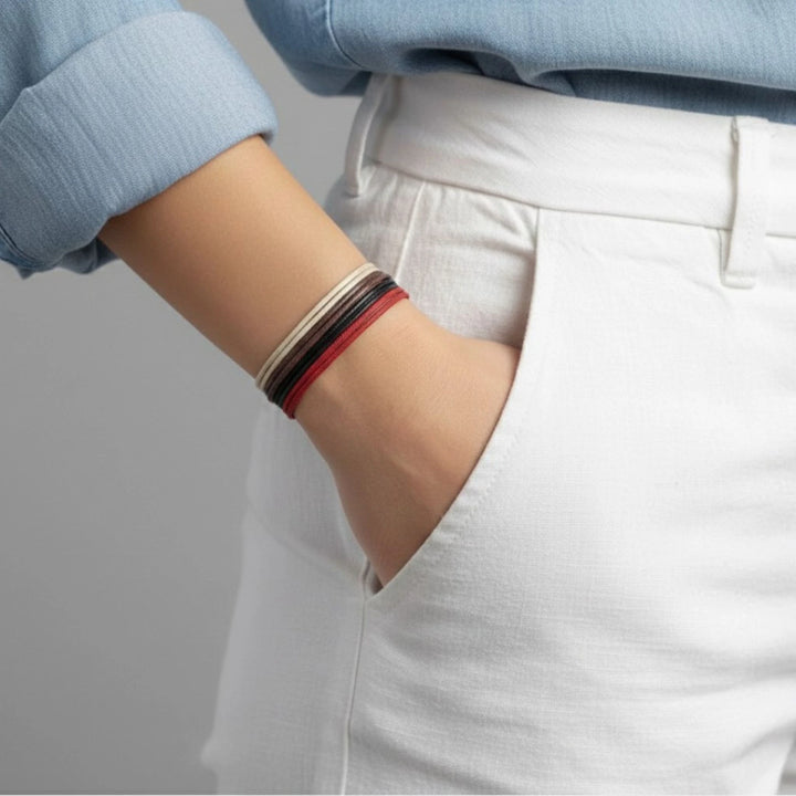 Person wearing a bracelet stack on a plain background