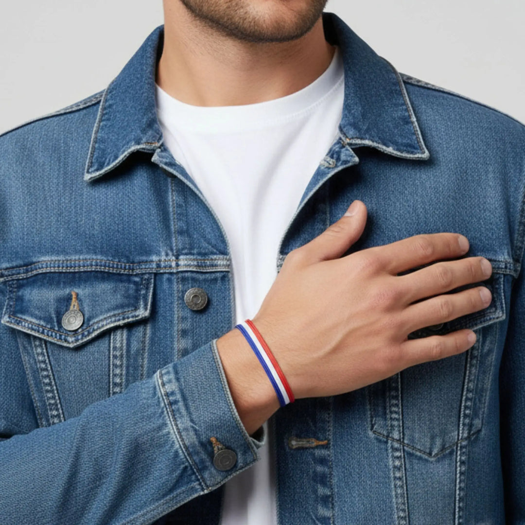 Person wearing a blue denim jacket with a hand on the chest, wearing a red, white, and blue bracelet.