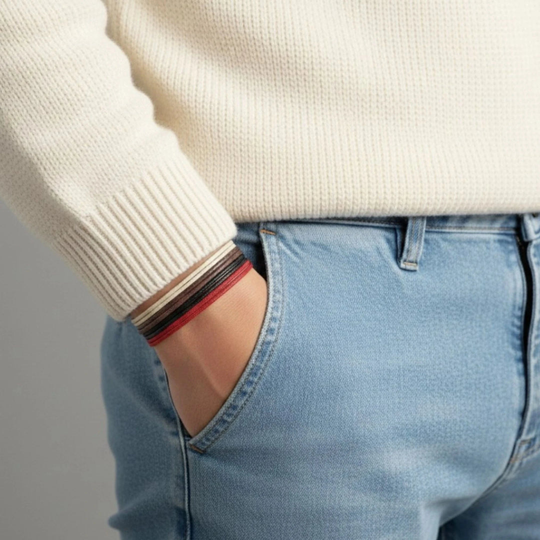 Person wearing a white sweater with a cord bracelet stack on a gray background