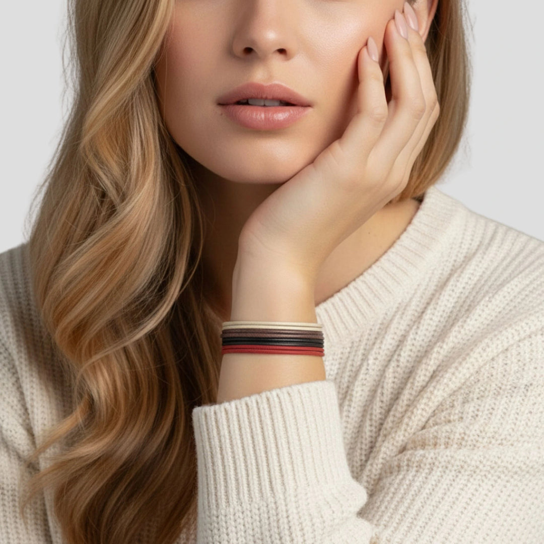 Woman wearing a cream sweater with a cord bracelet stack on a light background