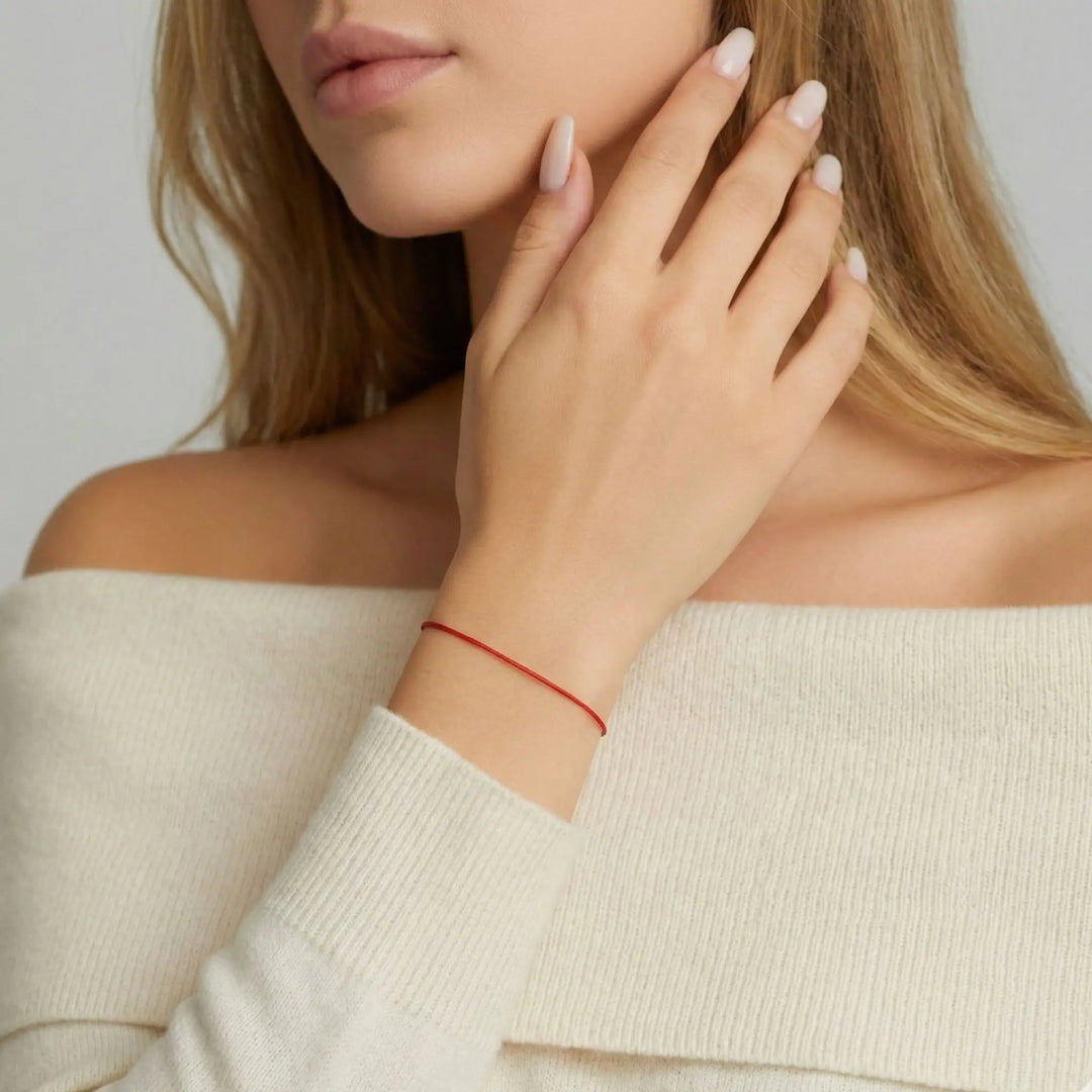 Woman wearing a red bracelet on a plain background