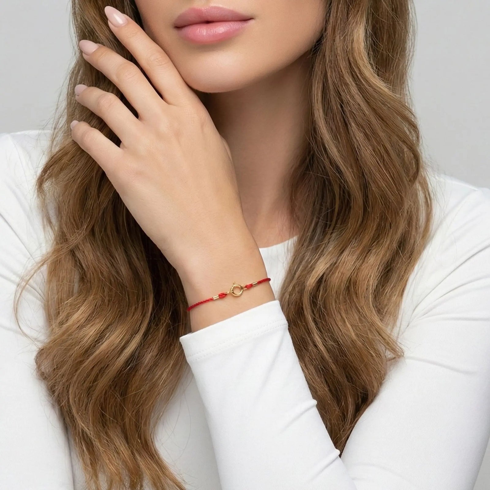 Woman wearing a red gold bracelet with a white background