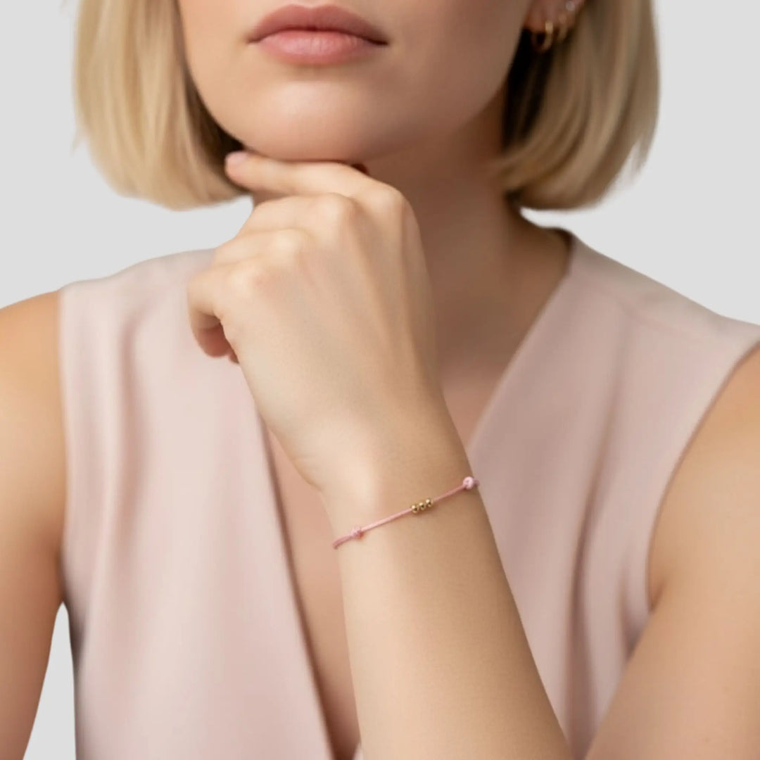 Woman wearing a pink bracelet on a plain background