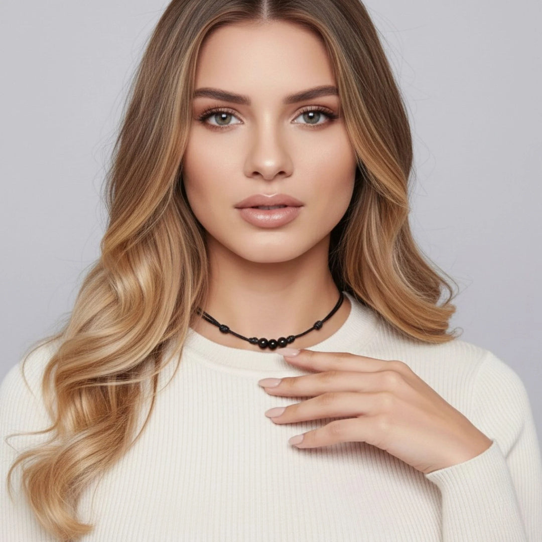 Woman with styled hair and a necklace against a plain background