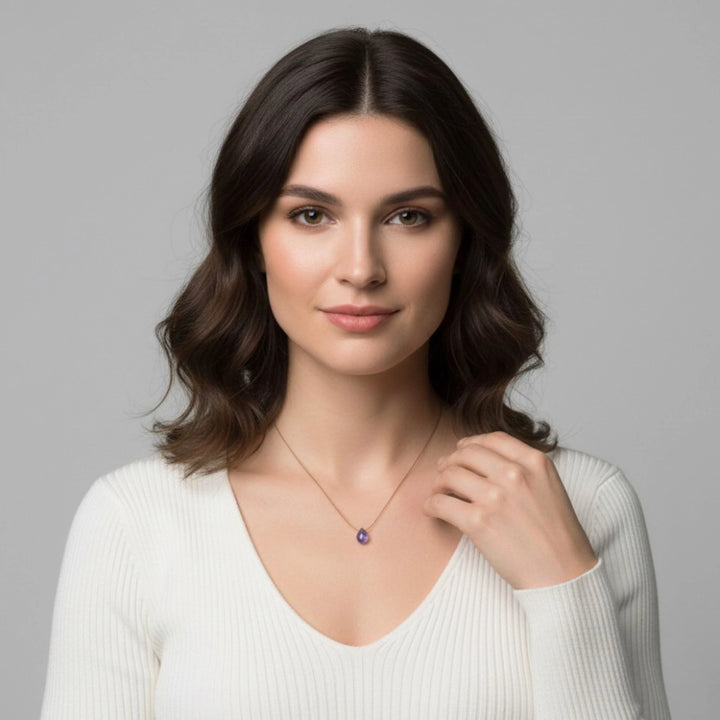 Woman wearing a necklace with a tanzanite pendant against a gray background