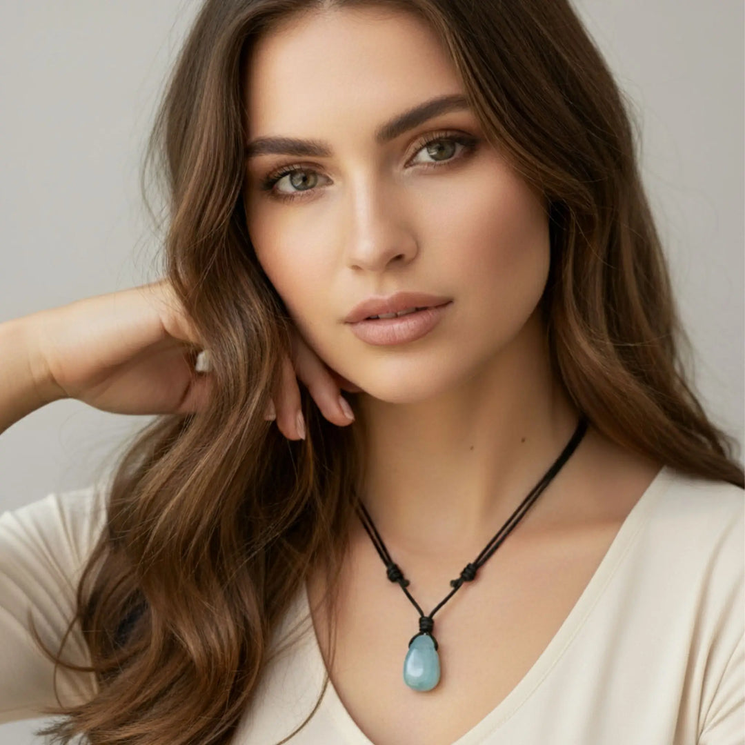 Woman wearing a necklace with a blue aquamarine pendant against a neutral background