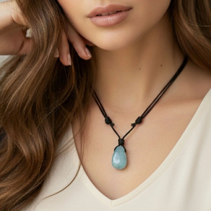Close-up of a woman wearing a necklace with a blue pendant.