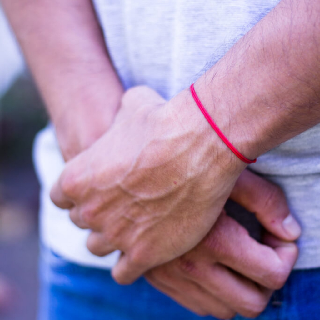 Man displaying a bracelet from the Two Pack Red String Bracelets, symbolizing connection and protection - Luck Strings