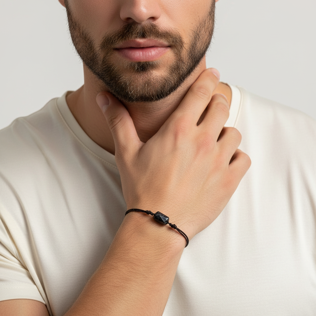 Man wearing raw black tourmaline bracelet on black cord, close-up lifestyle view.
